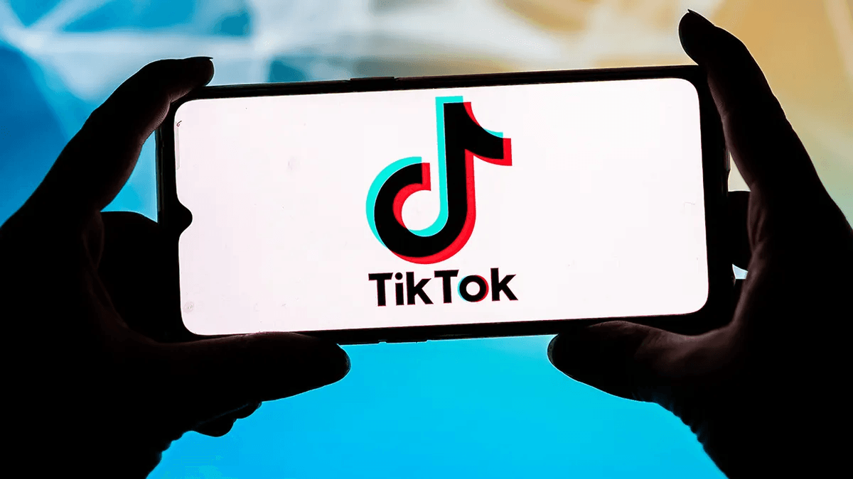 Hands holding a smartphone showing the TikTok logo